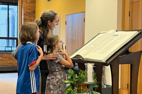 Mother and children reading from Saint Johns Bible at retreat.