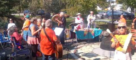 Church members playing drums and guitars in park.