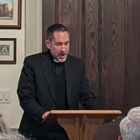 Priest speaking from podium